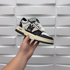 Black and white low-top sneakers with checkered strap and bold logo, beige sole.