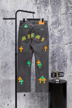 Dark gray denim pants with colorful cross patches and a graffiti-style print
