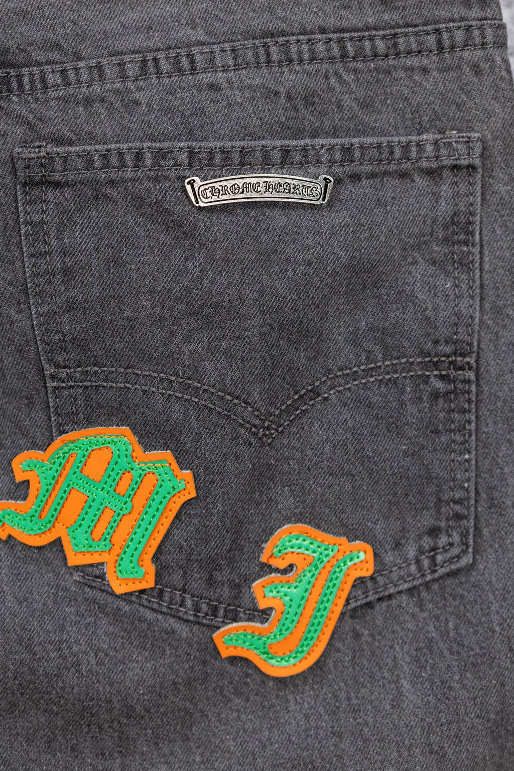 Dark gray denim pants with embroidered graphic patch on front pocket