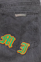 Dark gray denim pants with embroidered graphic patch on front pocket