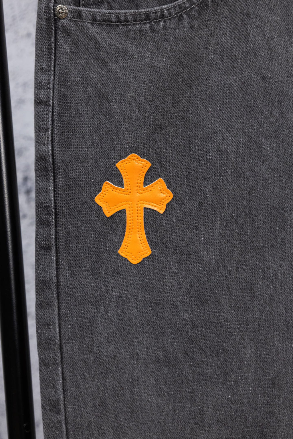 Dark gray denim pants with orange embroidered cross on side pocket