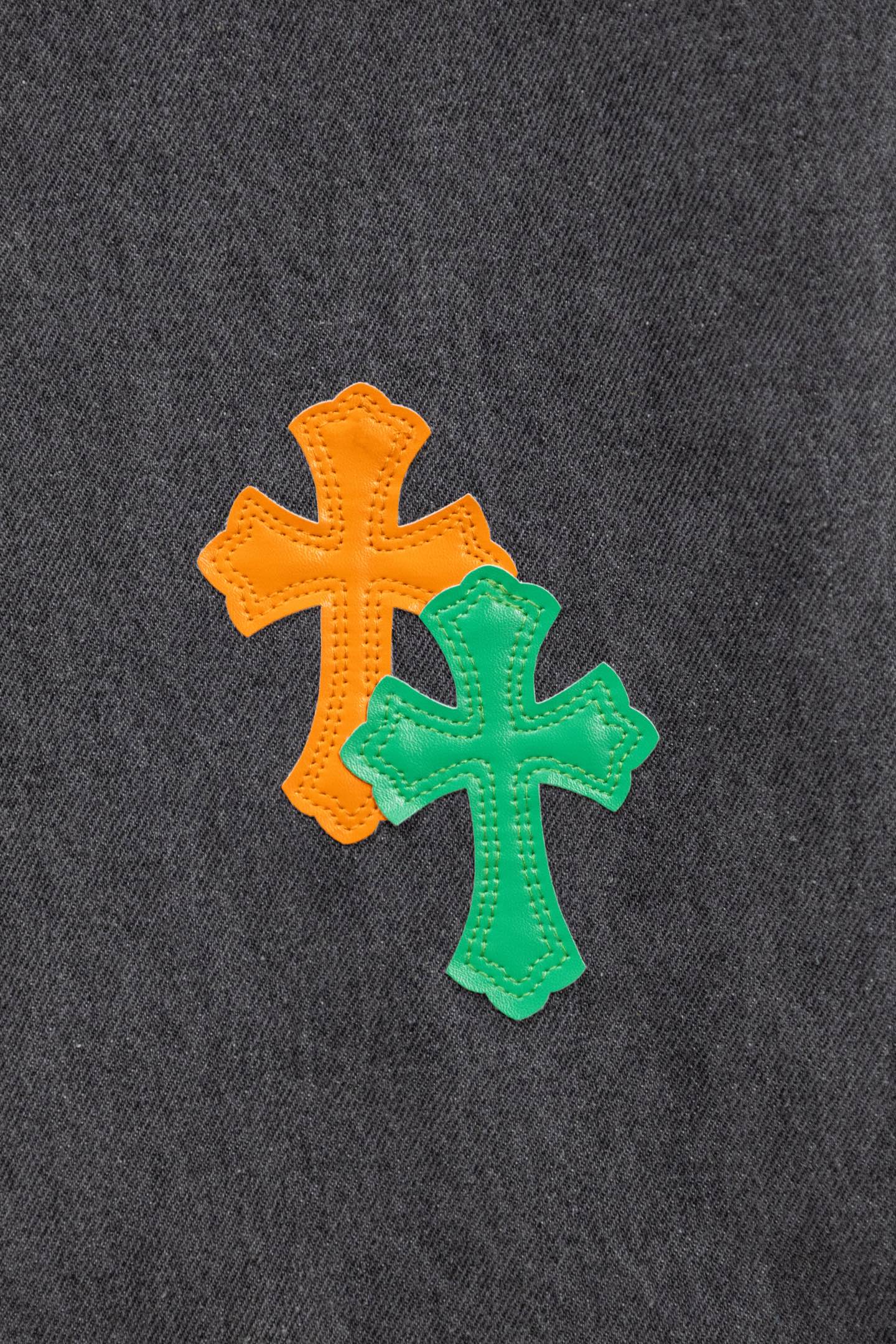 Dark gray denim pants with two cross patches in orange and green