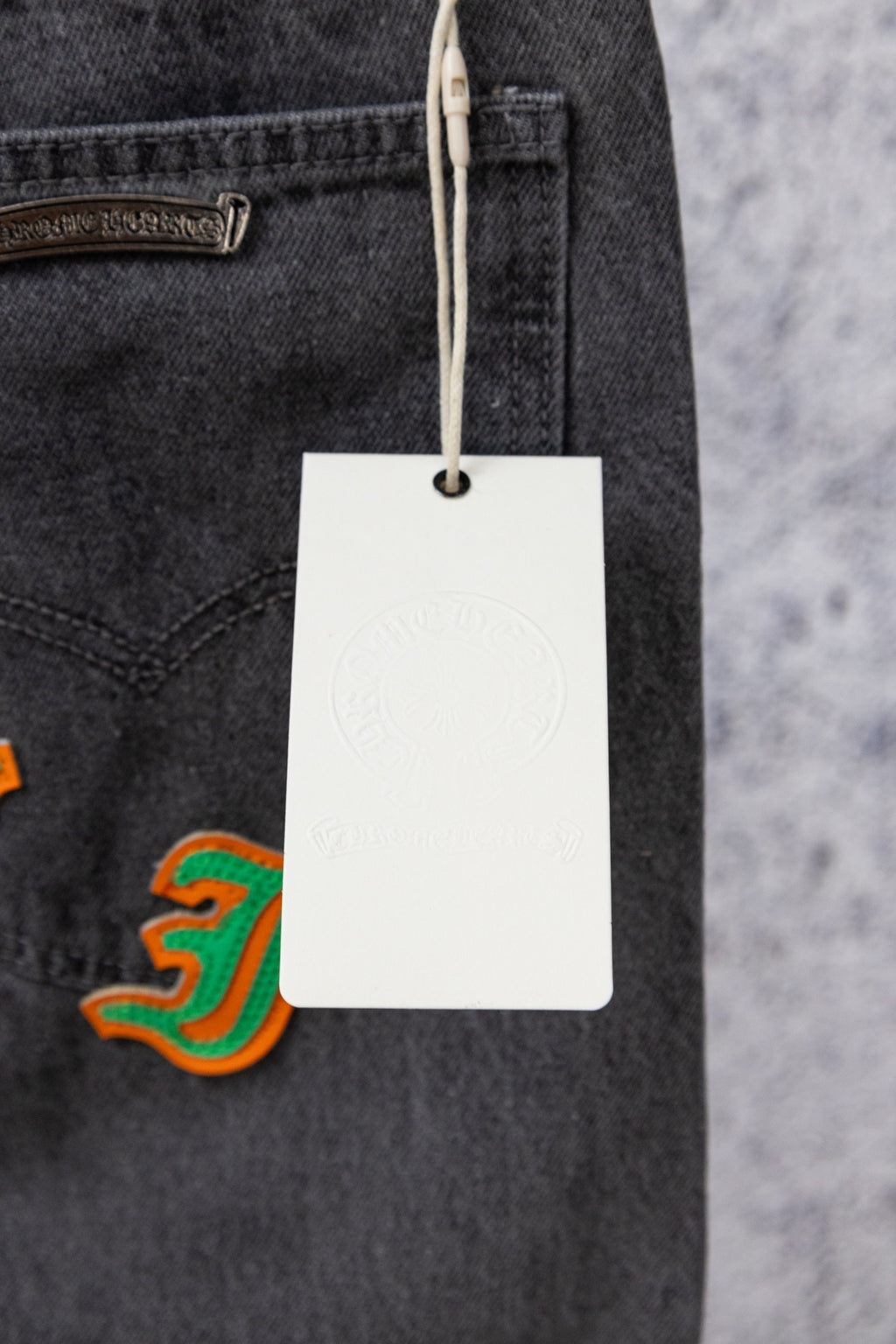 Dark gray denim jeans with hanging white price tag and pocket