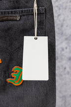 Dark gray denim jeans with hanging white price tag and pocket
