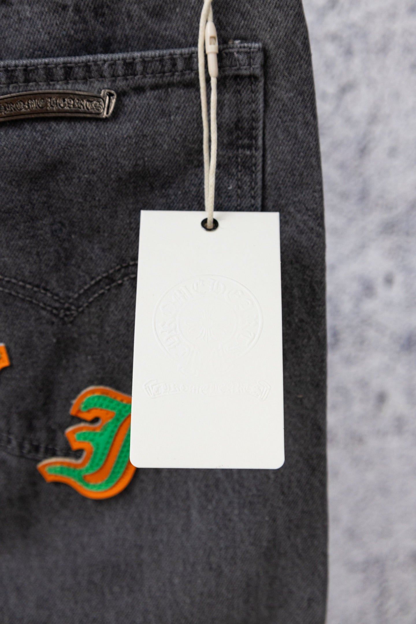 Dark gray denim jeans with hanging white price tag and pocket