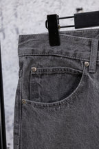 Dark gray denim pants with curved front pocket and metal button details