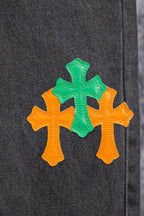 Dark gray denim pants with three cross patches in orange and green
