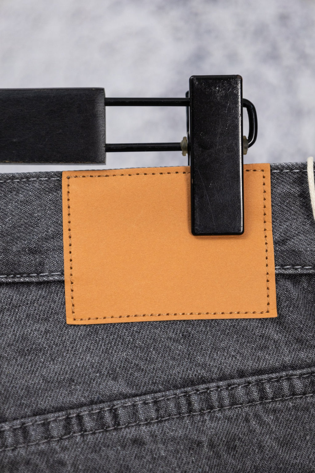 Dark gray denim pants with orange fabric patch and black belt clip