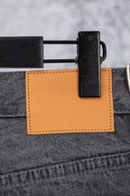 Dark gray denim pants with orange fabric patch and black belt clip