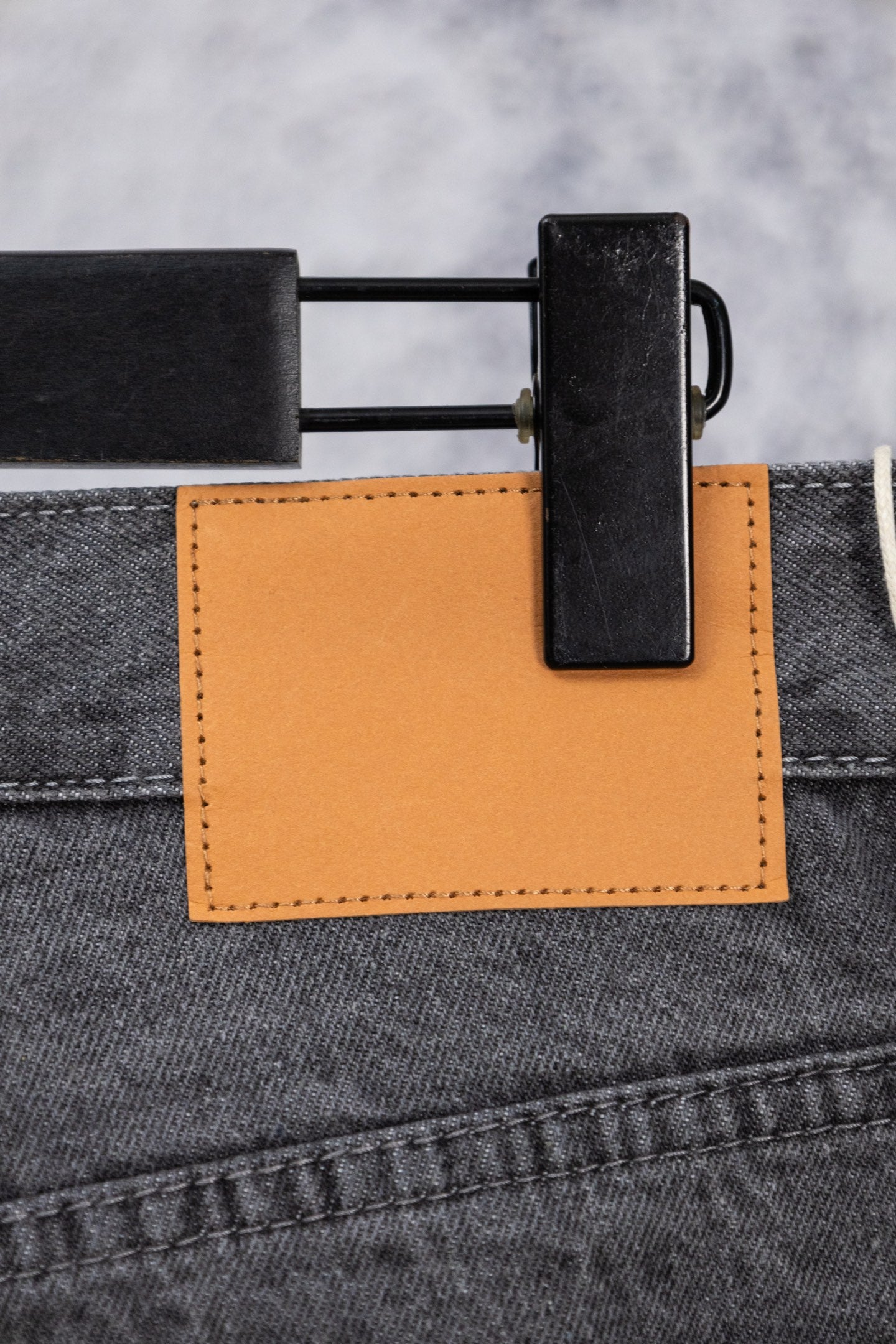 Dark gray denim pants with orange fabric patch and black belt clip