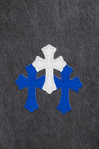 Chrome pants close-up of three blue-and-white cross patches on dark denim