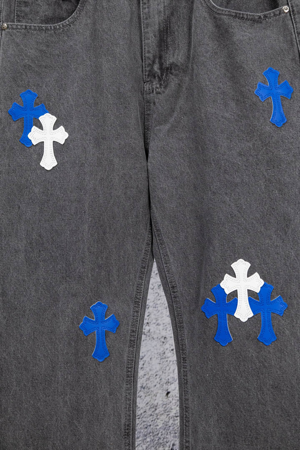 Gray denim pants front view with scattered blue and white cross patches.
