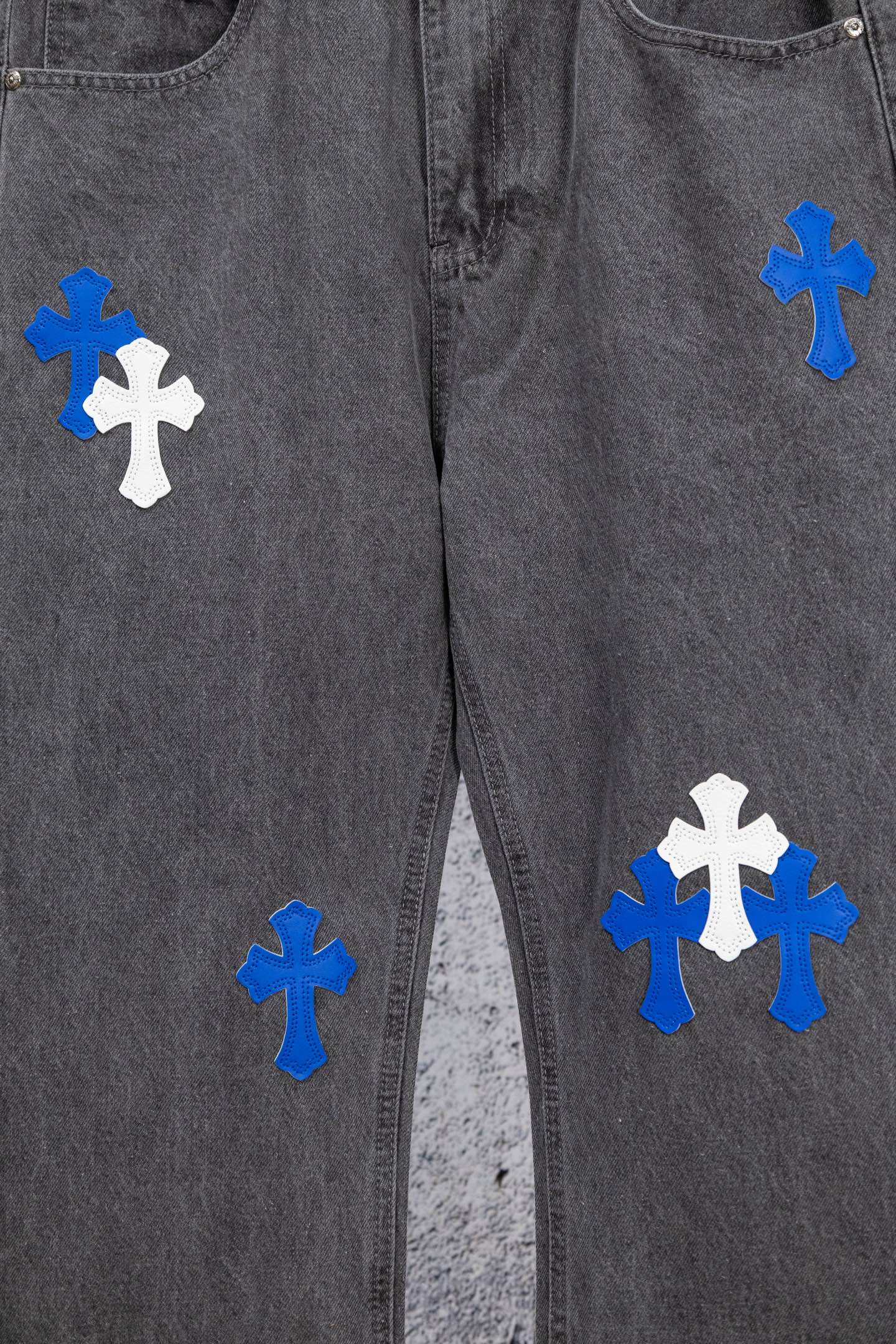 Gray denim pants front view with scattered blue and white cross patches.