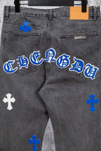 Close-up gray denim pants with blue-and-white cross graphic on the leg.