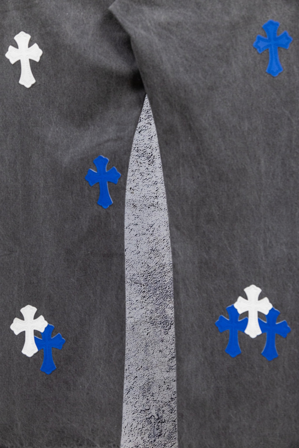 Chrome pants close-up with scattered blue cross appliques on dark denim