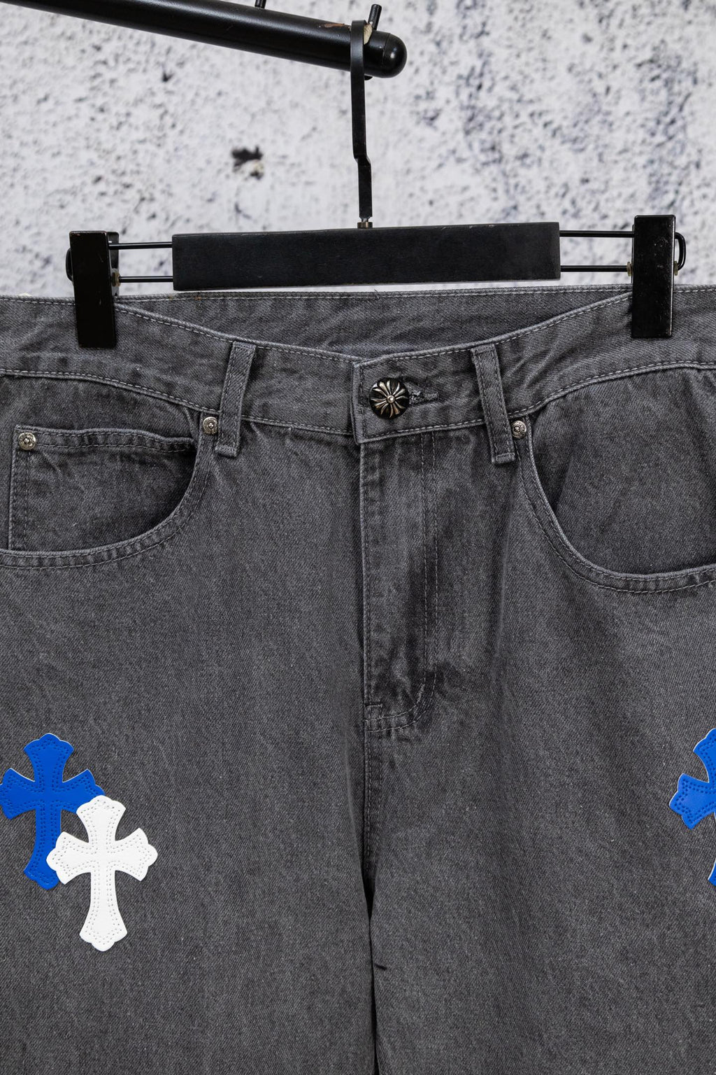 Gray denim pants with blue and white cross patches, waistband and front view.