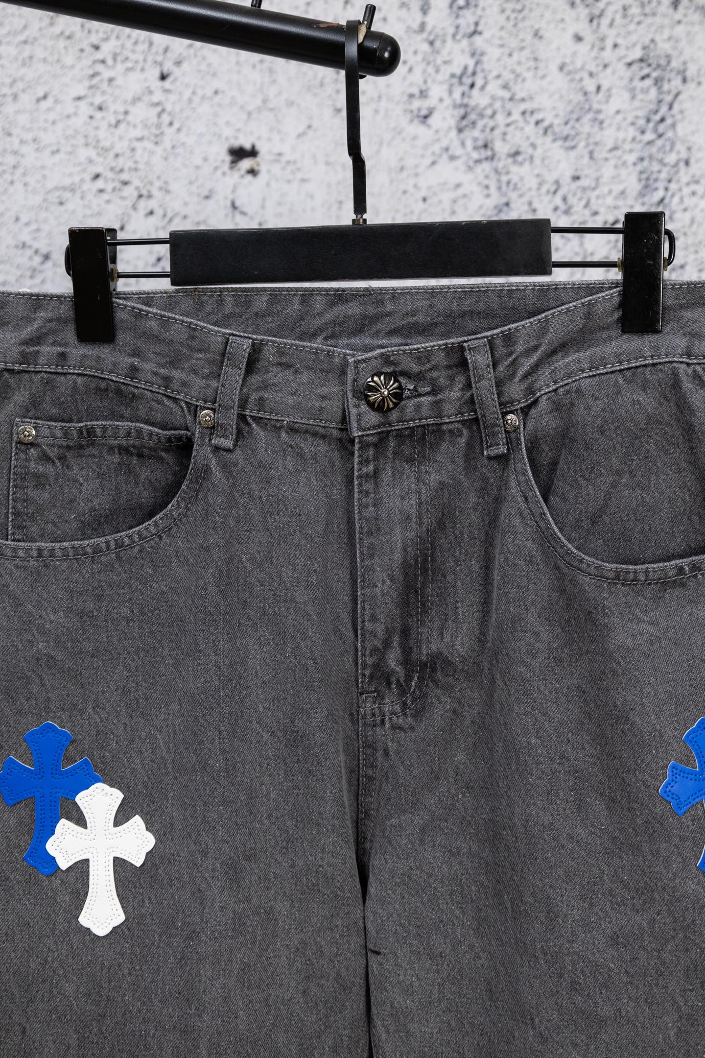Gray denim pants with blue and white cross patches, waistband and front view.