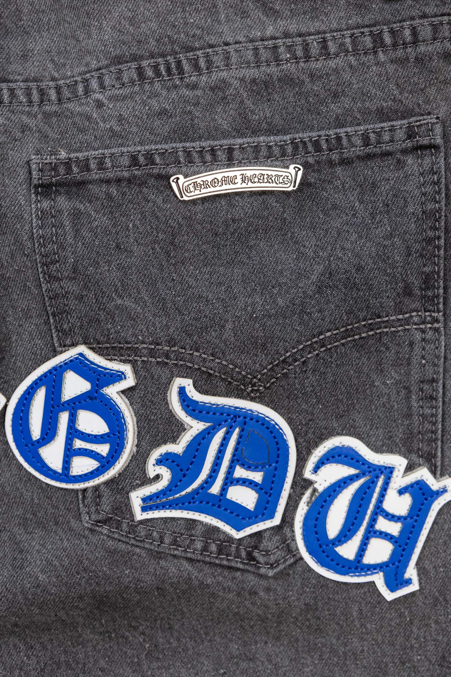 Chrome pants pocket close-up with stitched label and blue graphic lettering