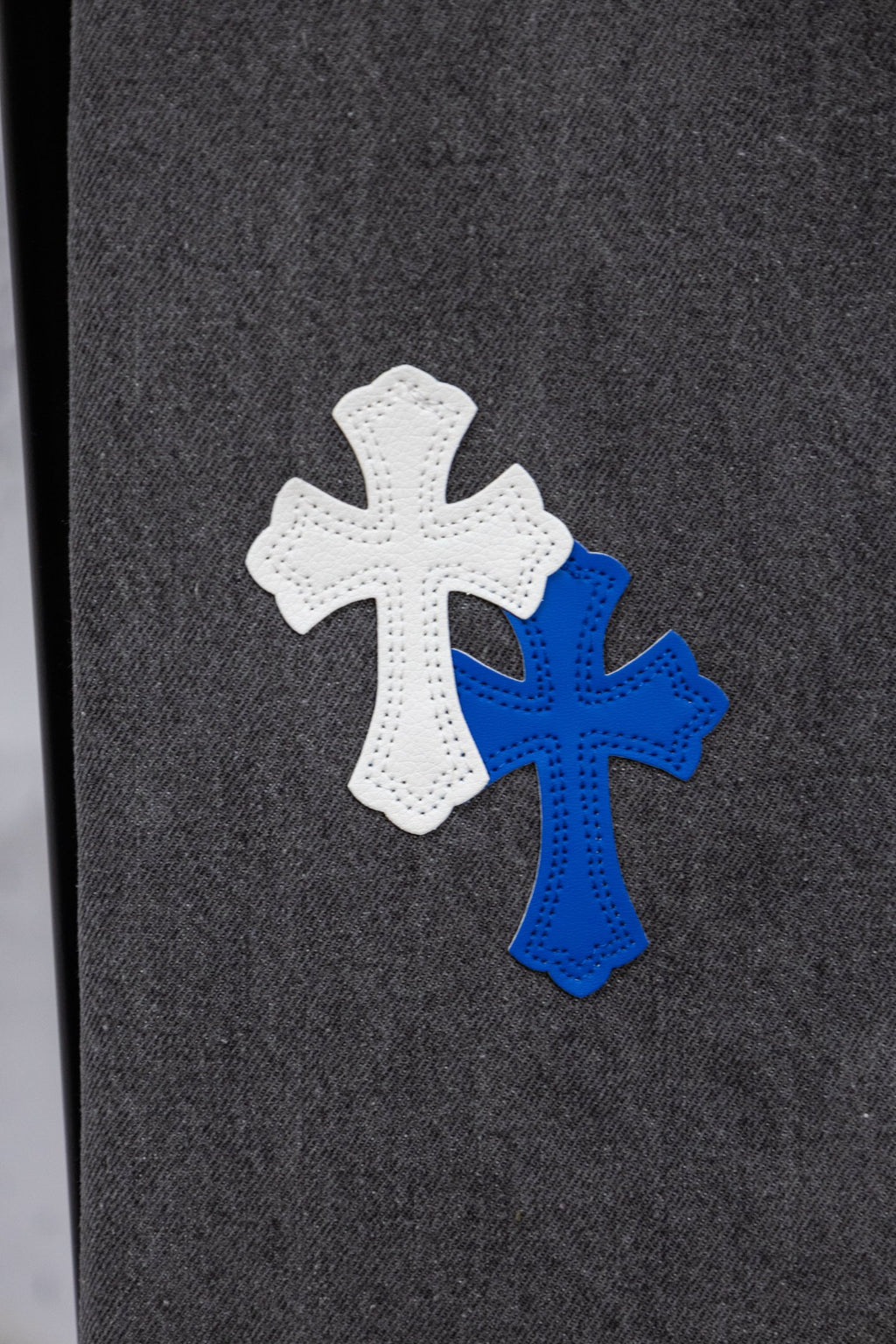 Chrome pants close-up of blue and white cross appliques on dark denim