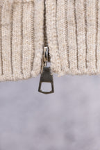 Cream ribbed sweater cuff with metal zipper tab close-up