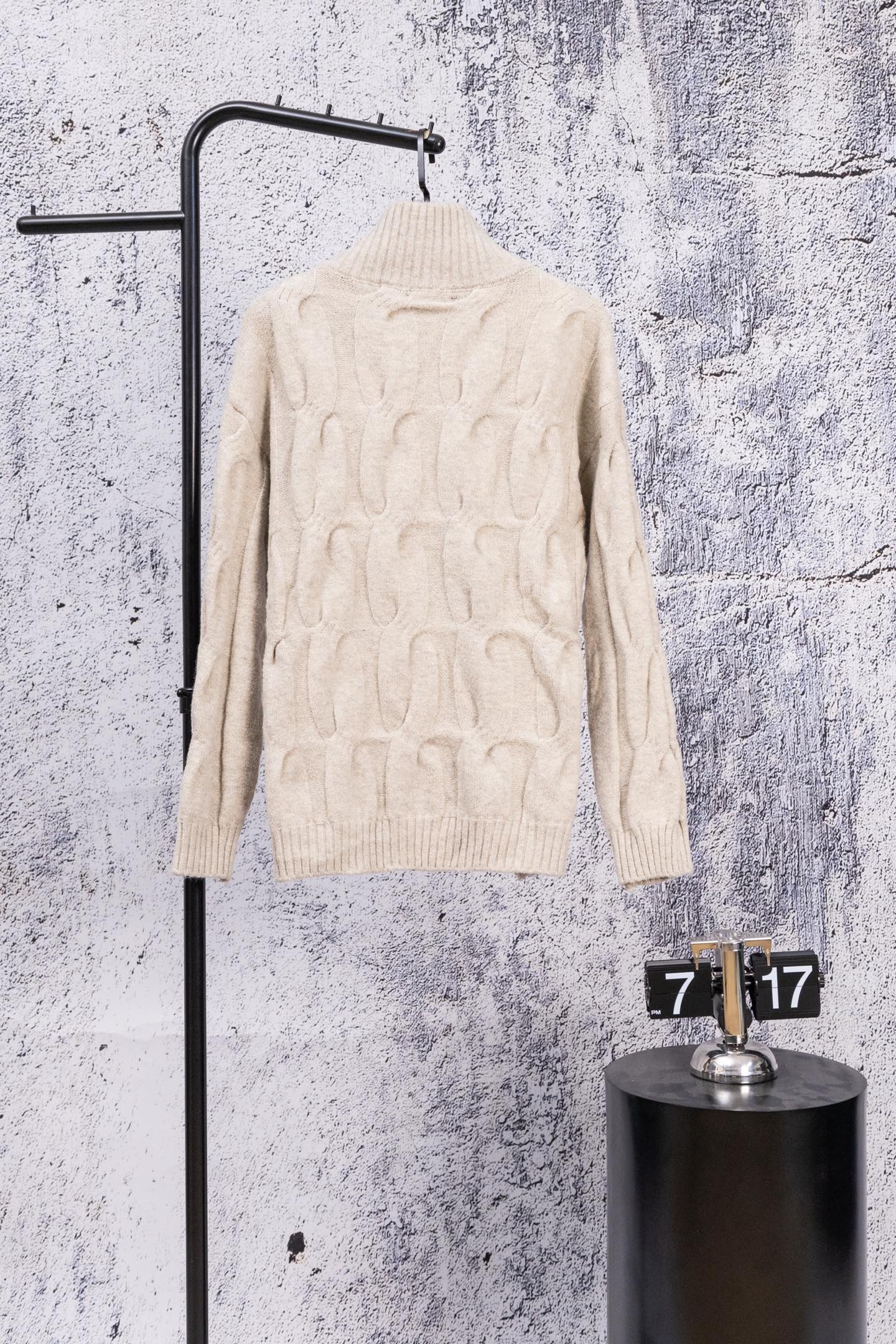 Cream cable-knit zip-up sweater with stand collar, back view on hanger