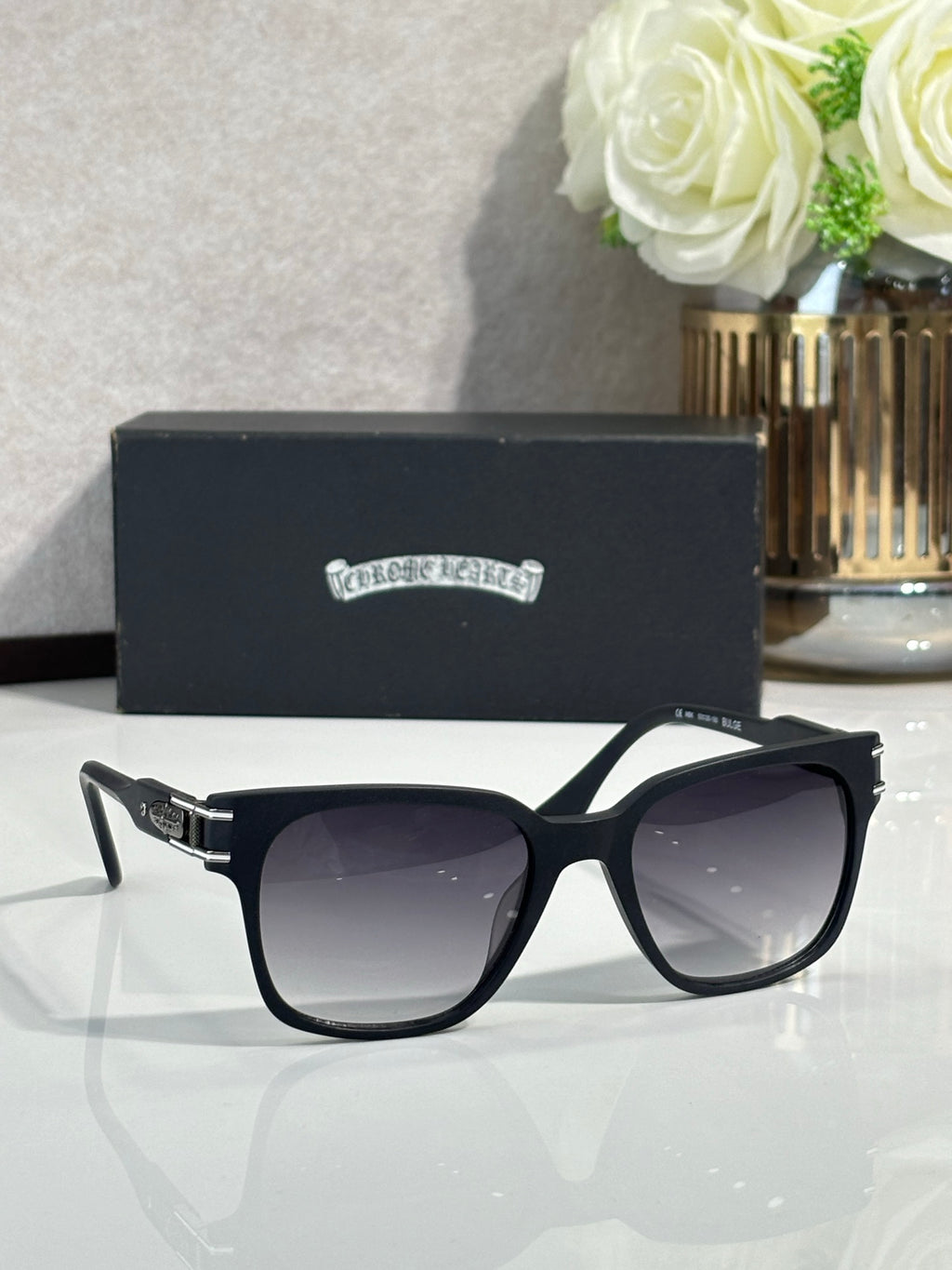 Black oversized sunglasses with dark lenses and engraved side logo