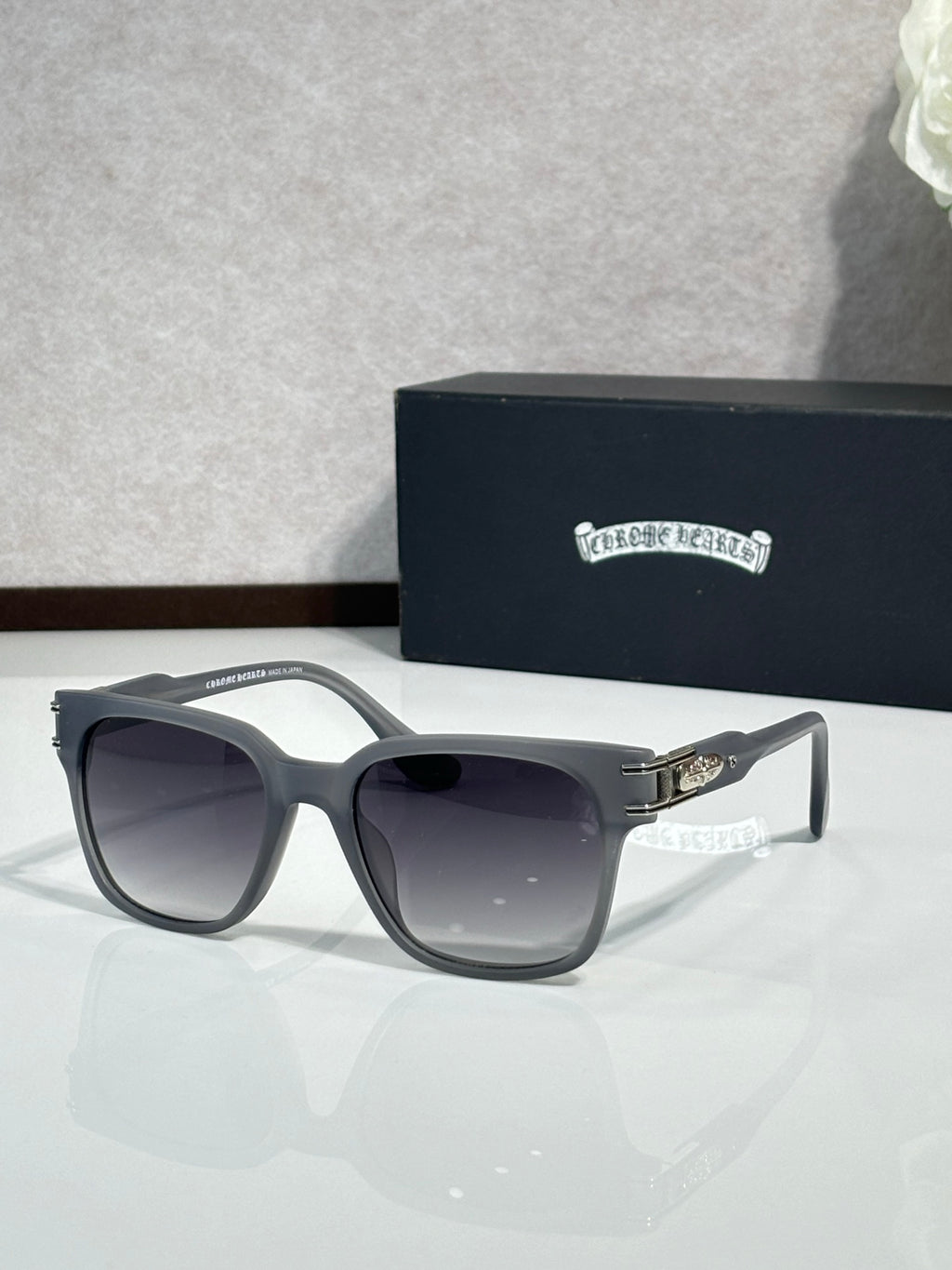 Black sunglasses with dark lenses and engraved temple branding, angled view