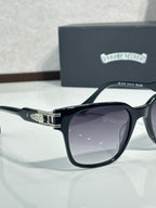 Black sunglasses with dark lenses, chrome-style hinge hardware, and engraved temple