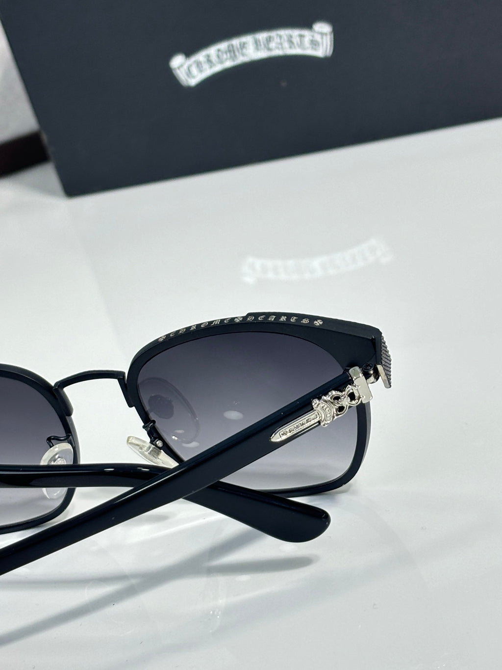 Sunglasses side close-up with dark lenses, black frame, logo temple and hinge