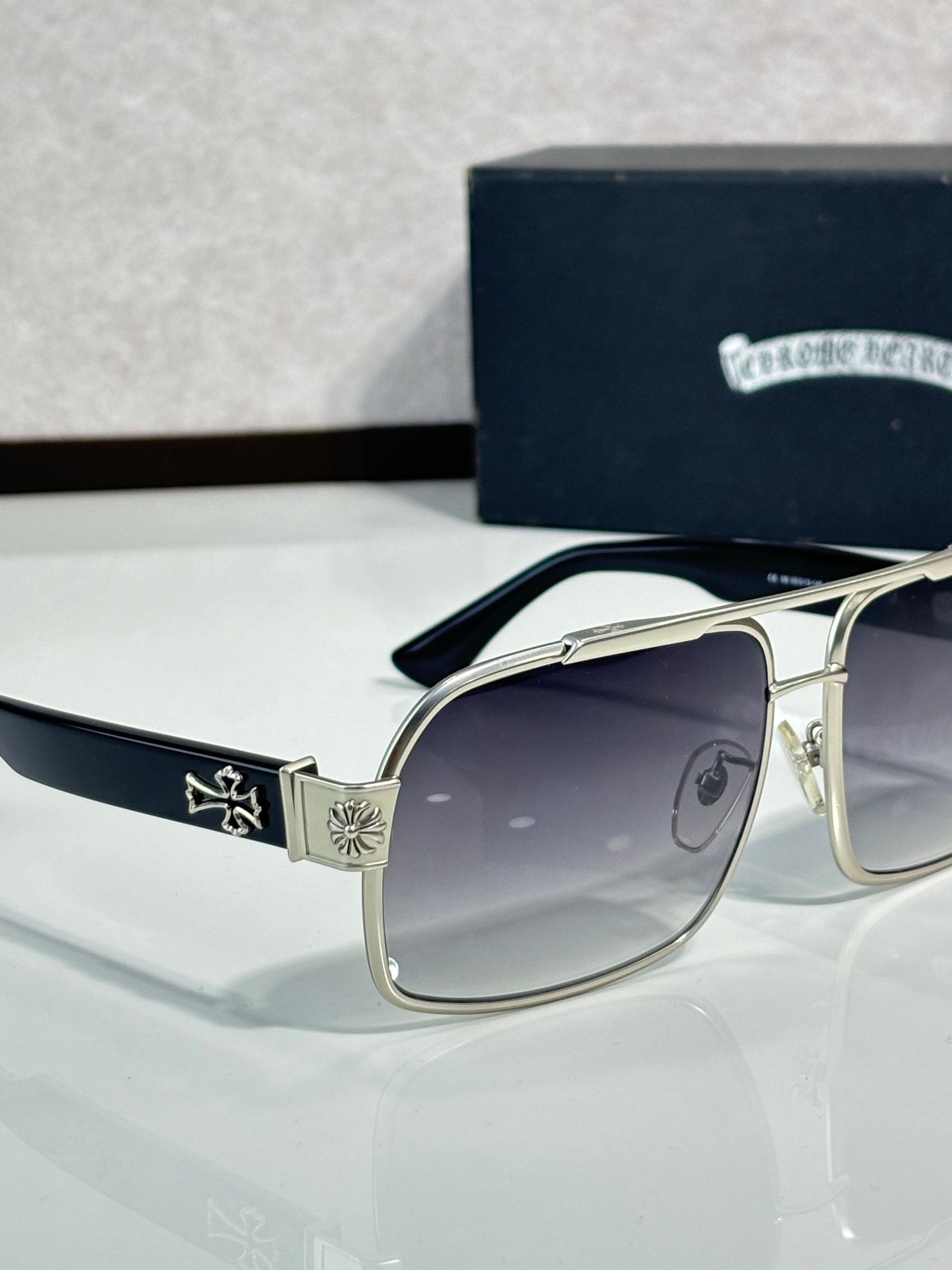 Gold sunglasses with dark lenses, square frames, and decorative side motifs