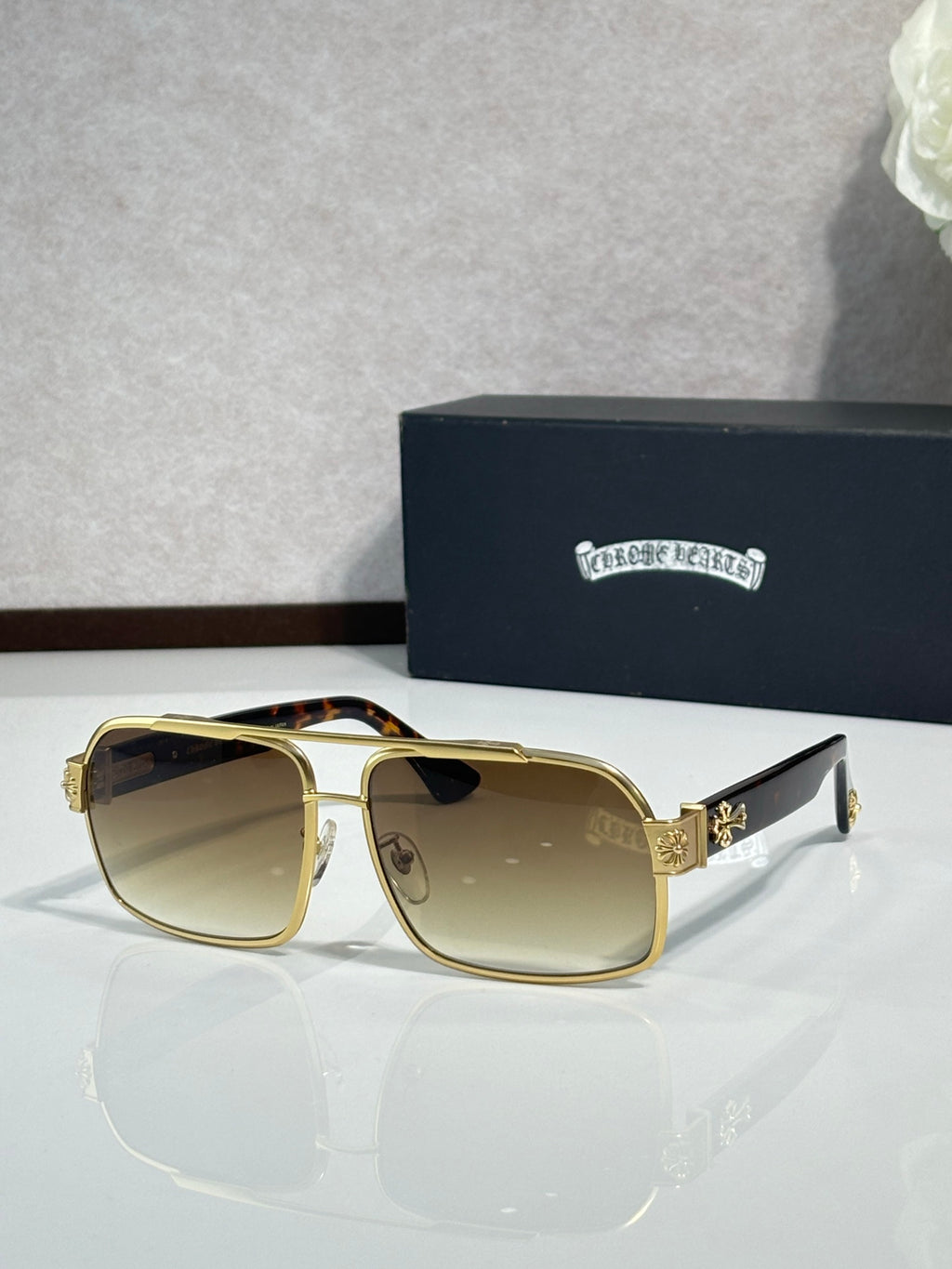 Gold square sunglasses with tinted lenses and rhinestone logo detail