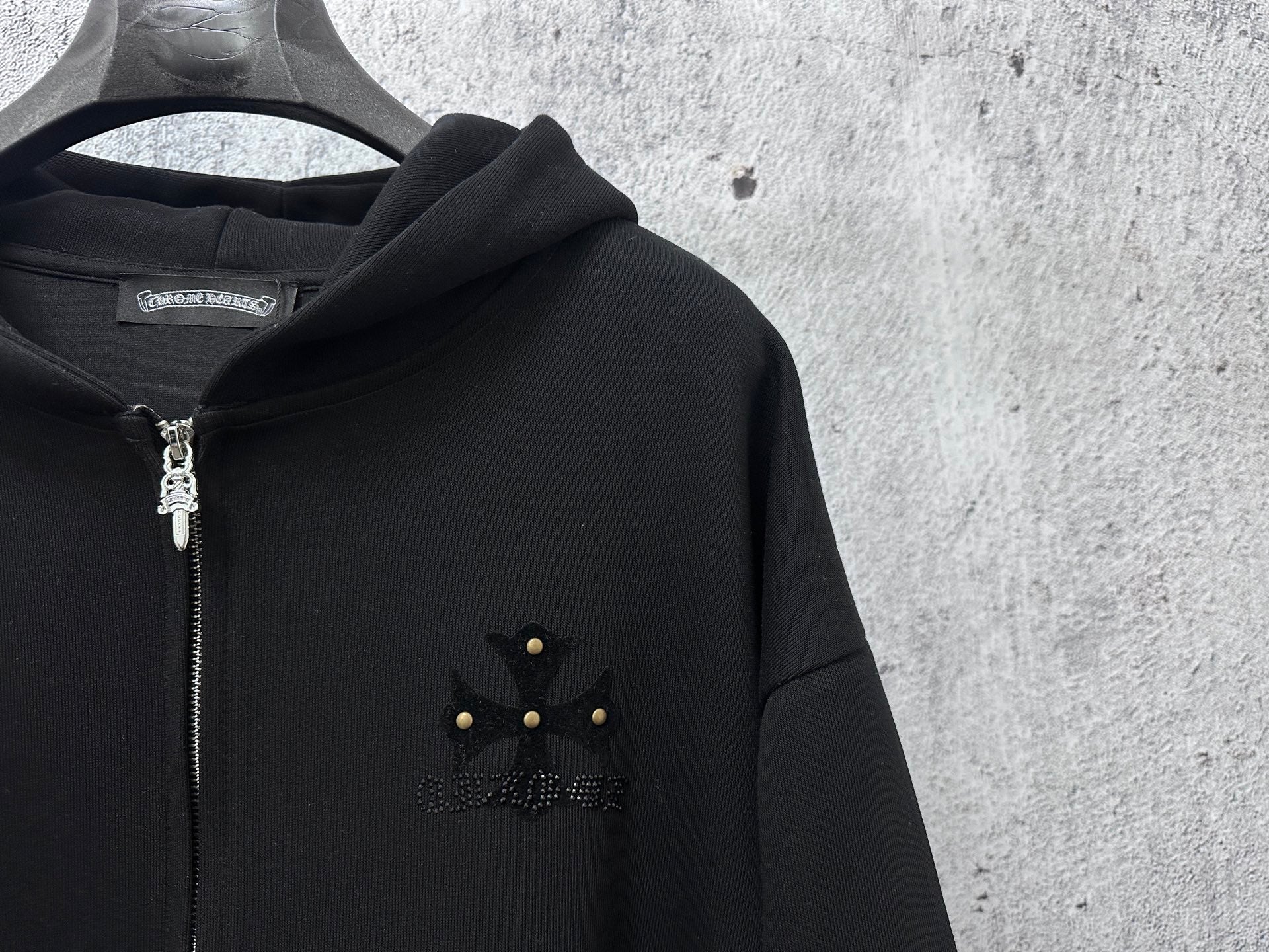Black zip-up hoodie with rhinestone chest emblem and silver zipper detail