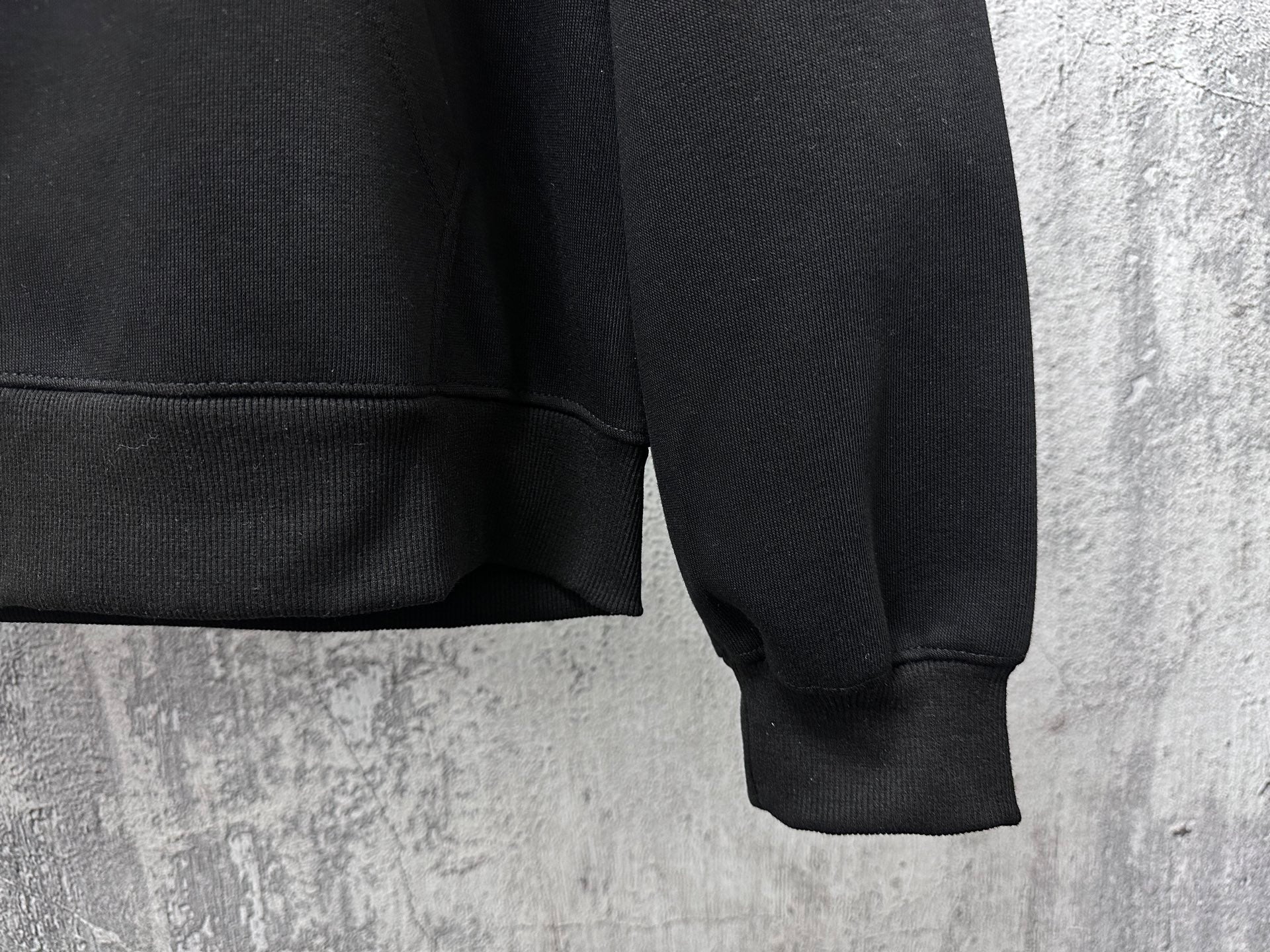 Black zip-up hoodie cuffs and hem with ribbed sleeve ends and pocket seam
