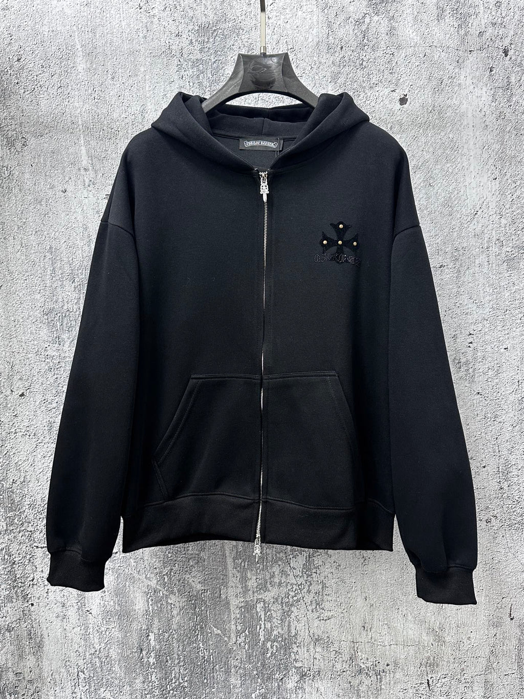 Black zip-up hoodie with hood, front zipper, kangaroo pocket and small chest emblem