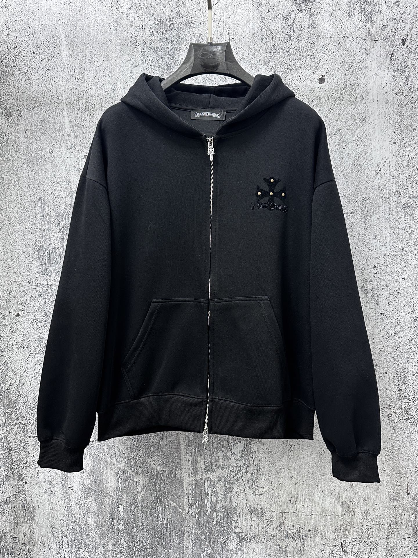 Black zip-up hoodie with hood, front zipper, kangaroo pocket and small chest emblem