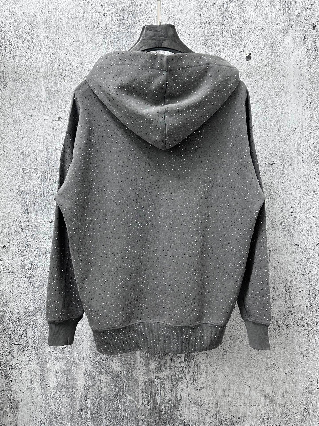 Long-sleeve hoodie back view, dark gray with attached hood and speckled dots