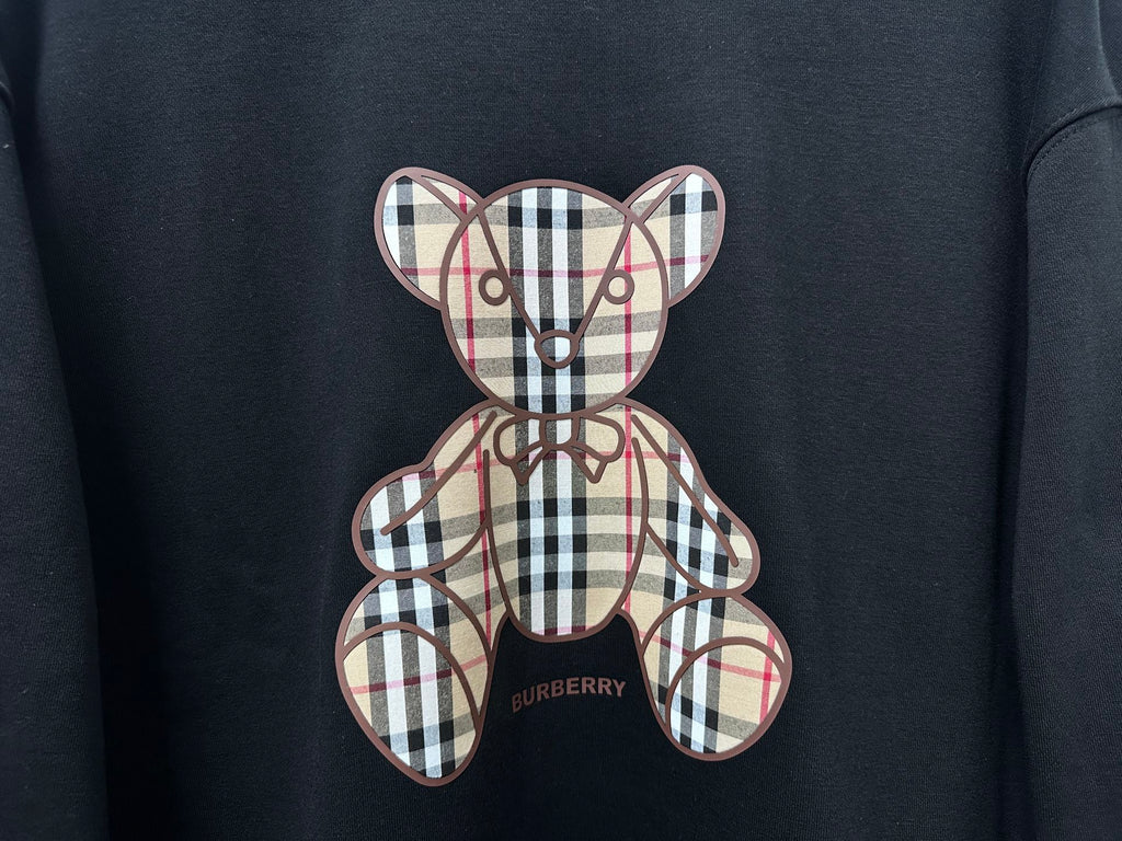 Black sweatshirt close-up of plaid teddy bear applique and Burberry logo