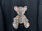 Black sweatshirt close-up of plaid teddy bear applique and Burberry logo
