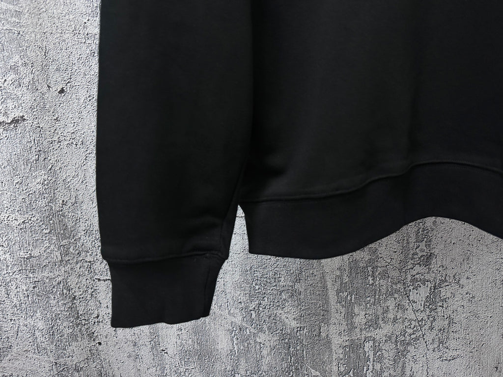 Black sweatshirt hem detail with ribbed cuffs and side seam