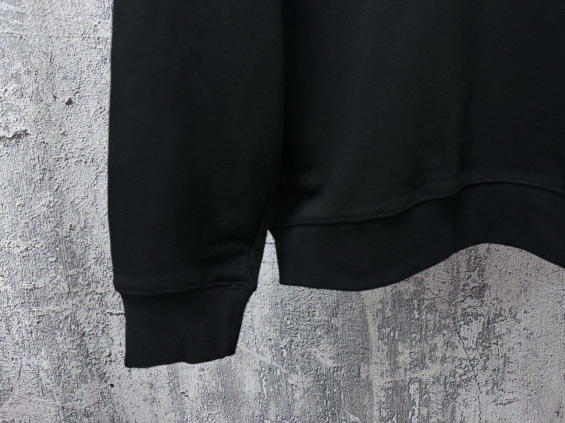 Black sweatshirt hem detail with ribbed cuffs and side seam