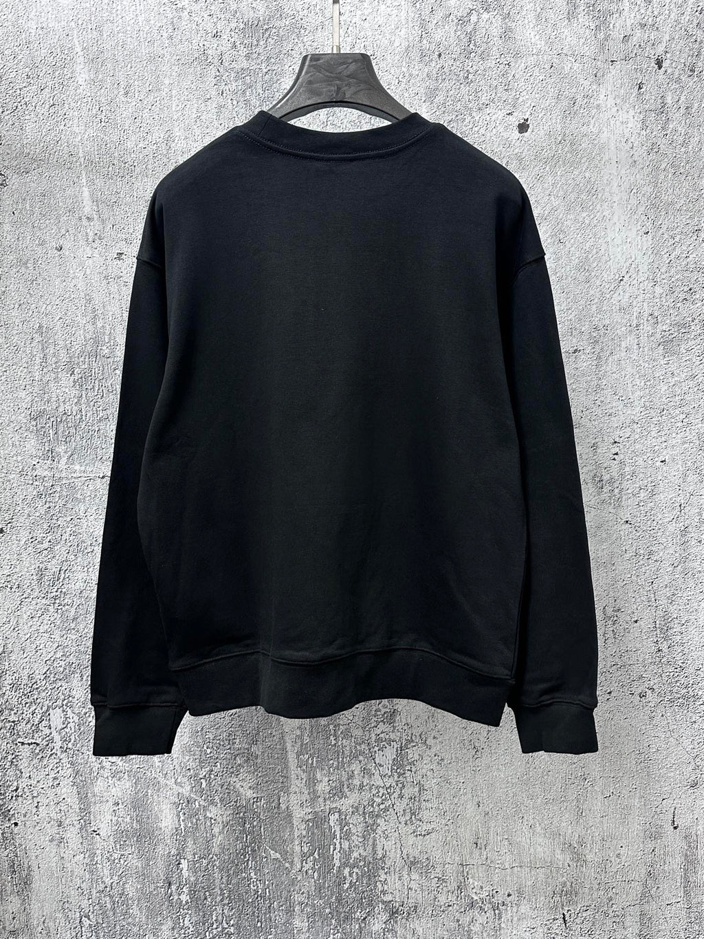 Black long-sleeve sweatshirt back view, crew neck and ribbed cuffs