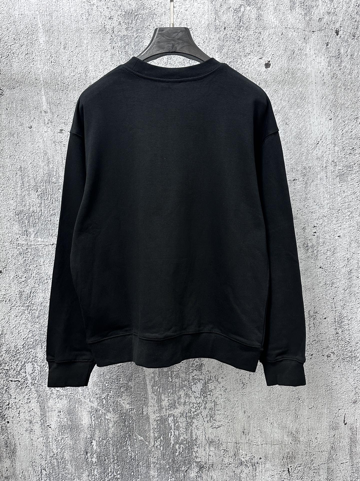 Black long-sleeve sweatshirt back view, crew neck and ribbed cuffs