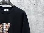 Black sweatshirt with partial plaid teddy bear graphic on chest