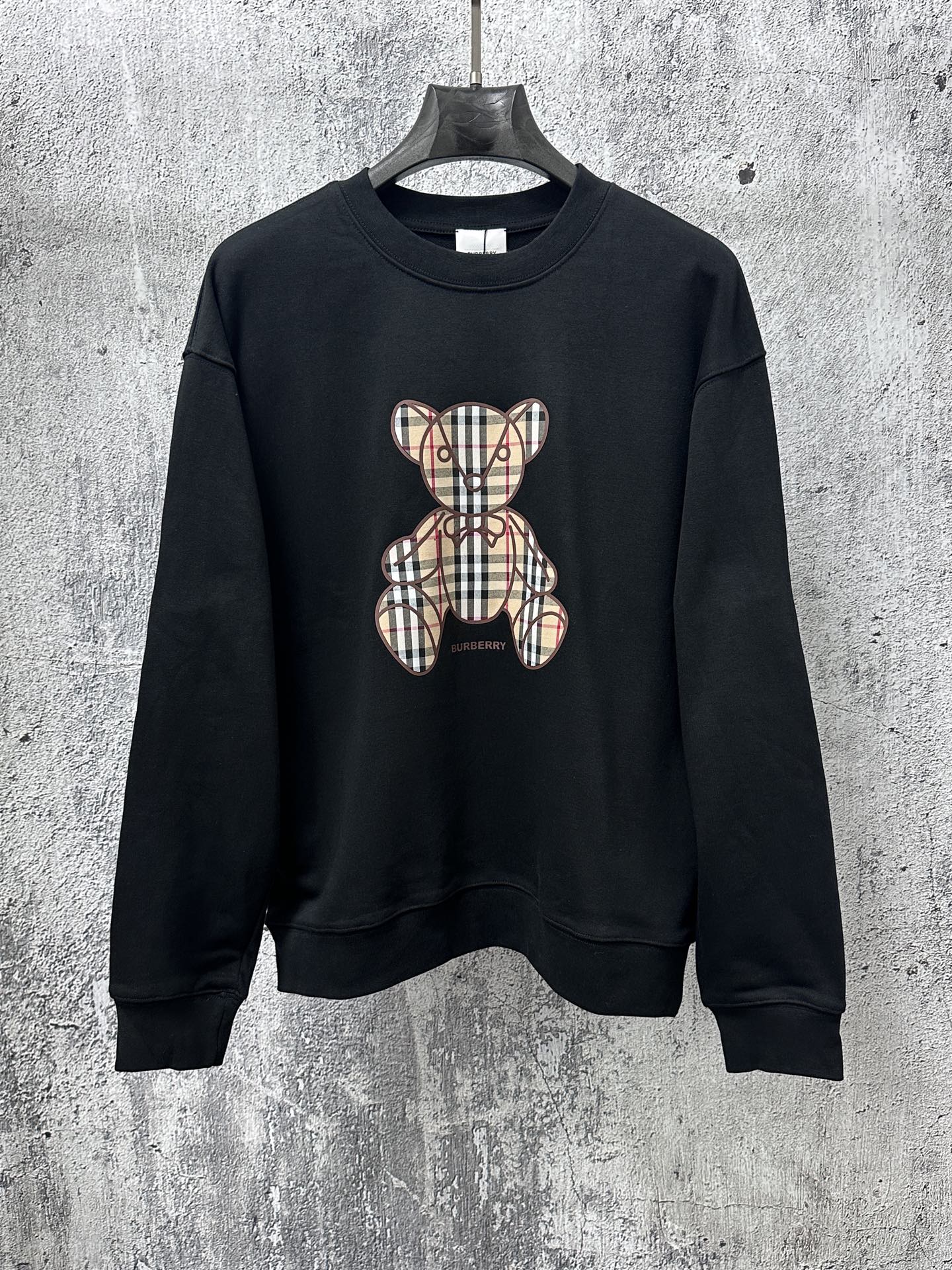Black long-sleeve sweatshirt with plaid teddy bear graphic on front