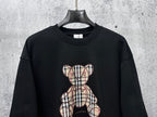 Black long-sleeve sweatshirt with full plaid teddy bear patch and bow