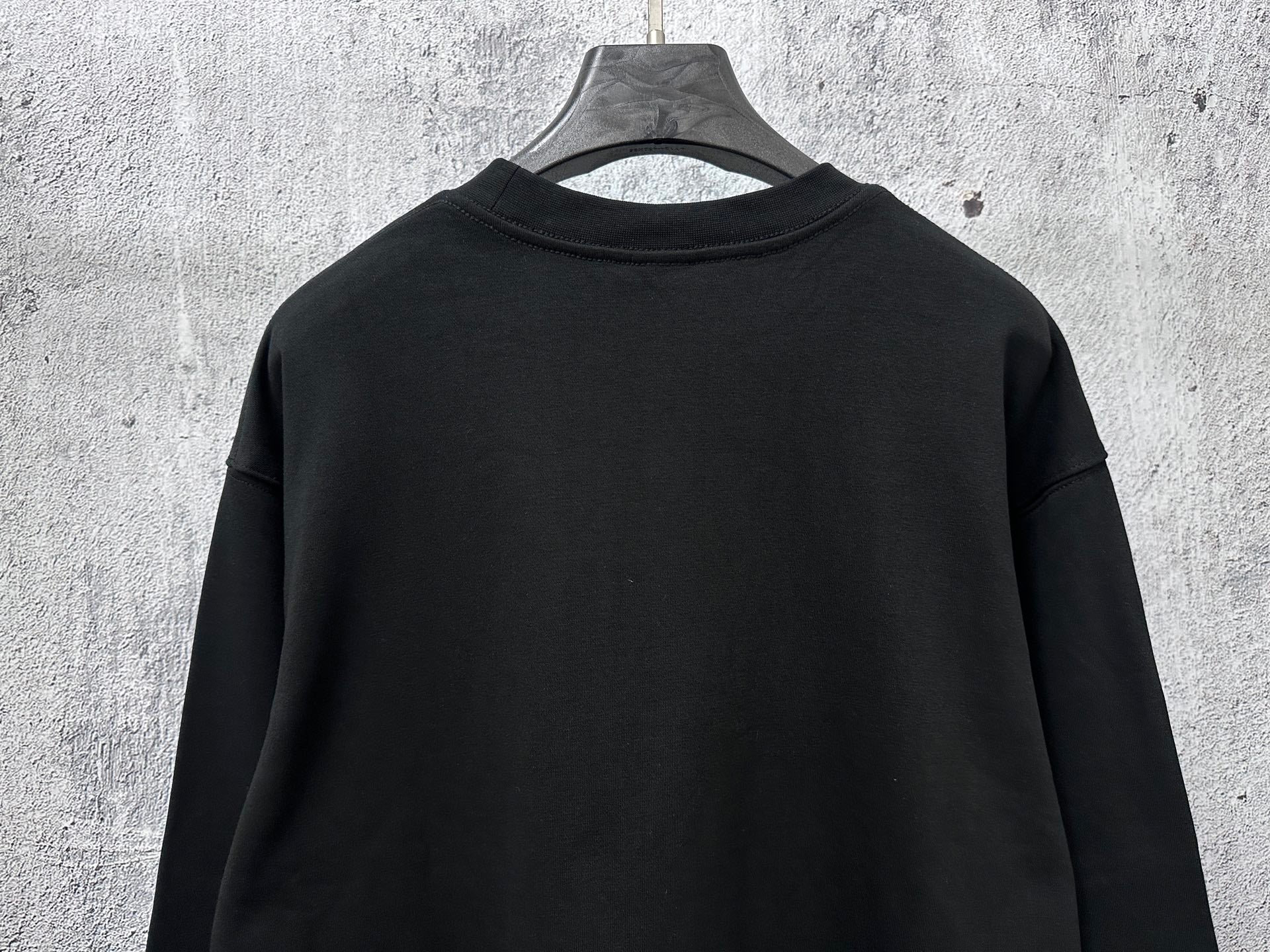 Black long-sleeve sweatshirt back view with ribbed neckline and hem