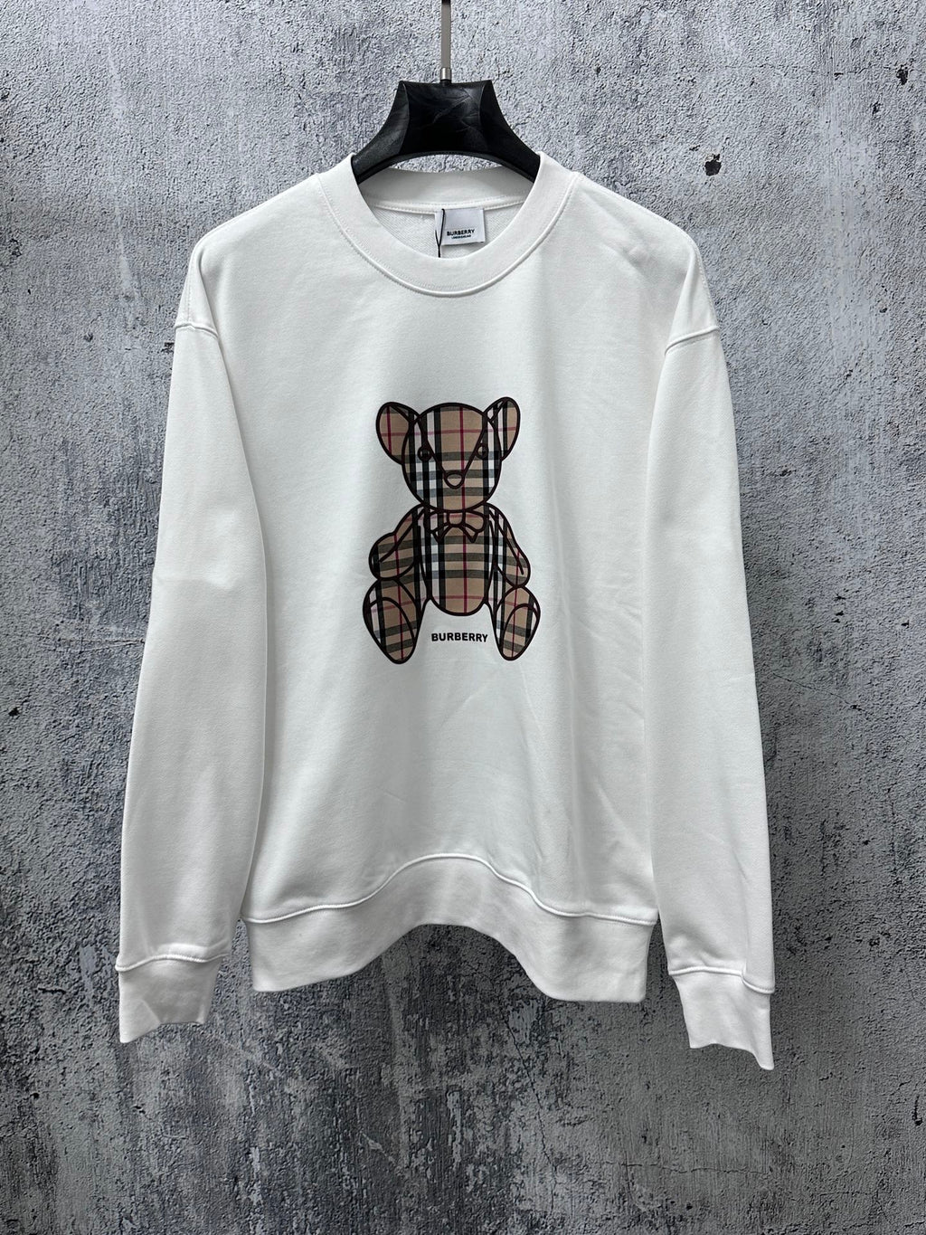 White crewneck long-sleeve sweatshirt with Burberry check-style teddy graphic on front