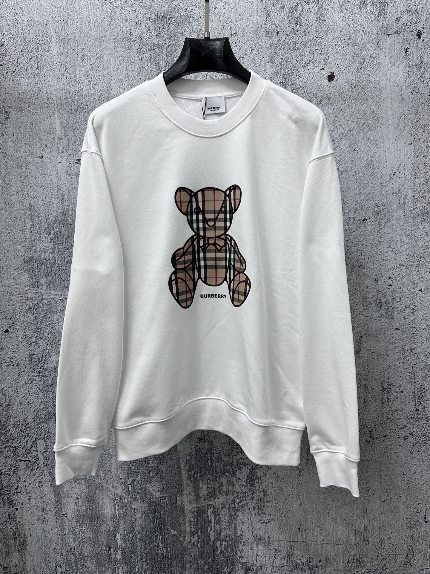 White crewneck long-sleeve sweatshirt with Burberry check-style teddy graphic on front