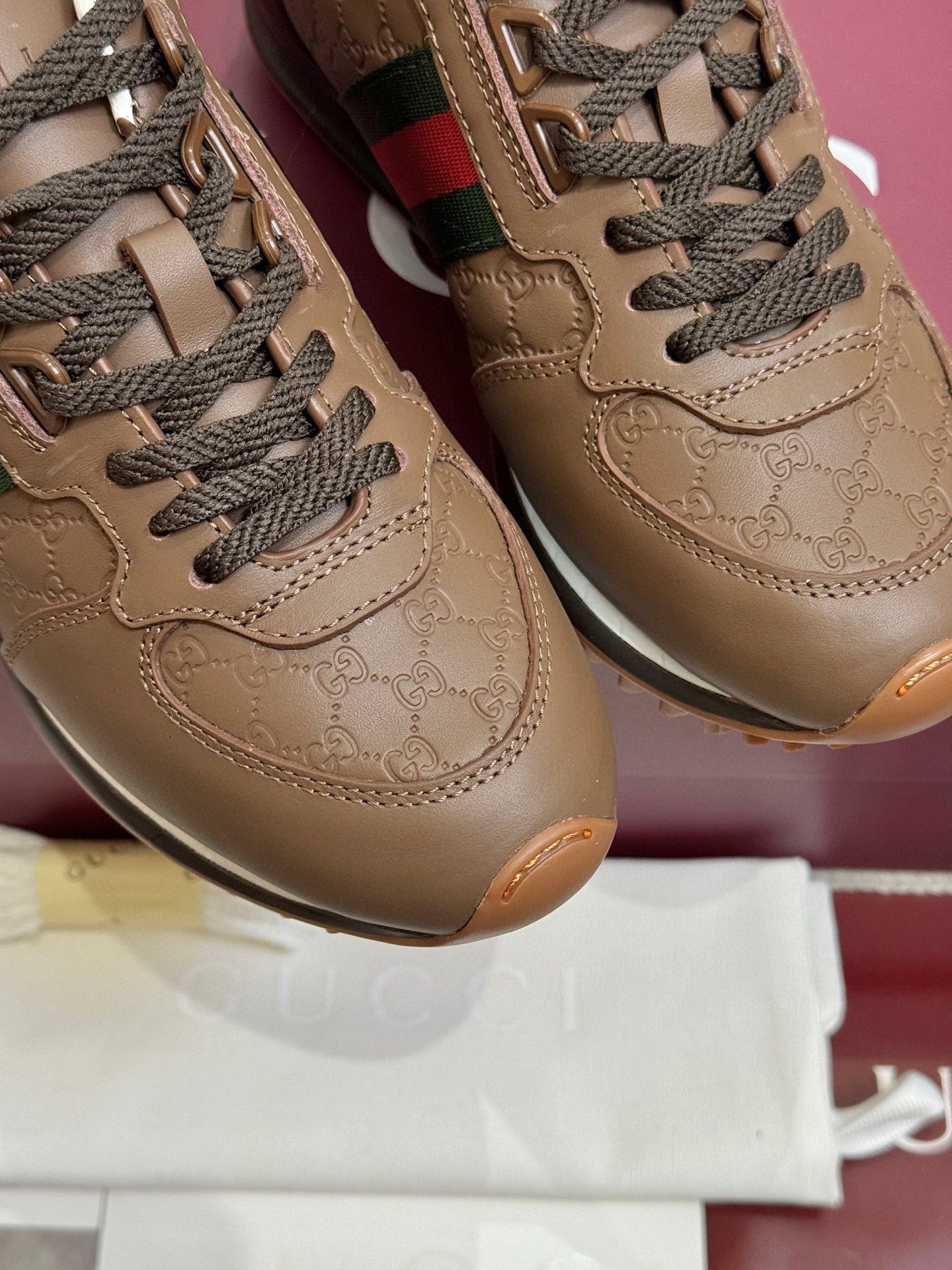 Gucci unisex leather sneakers close-up, tan embossed logo and braided laces