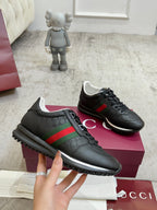 Gucci unisex sneakers, black lace-up with green and red stripe, textured emblem upper